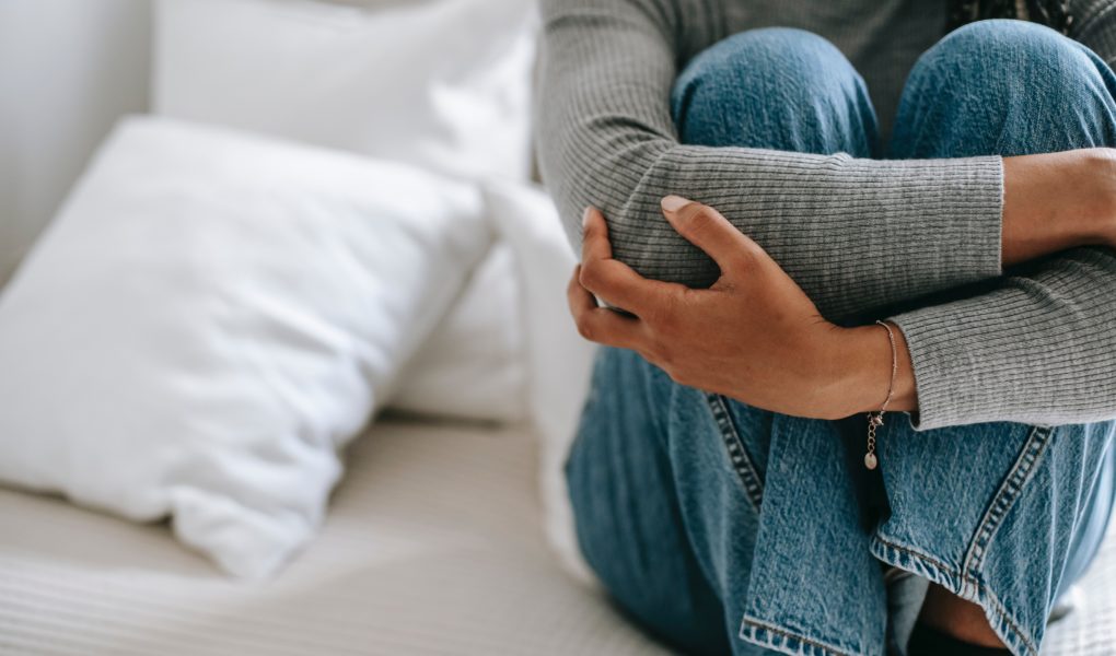femme se tient les jambes sur son lit car elle a des douleurs vaginales
